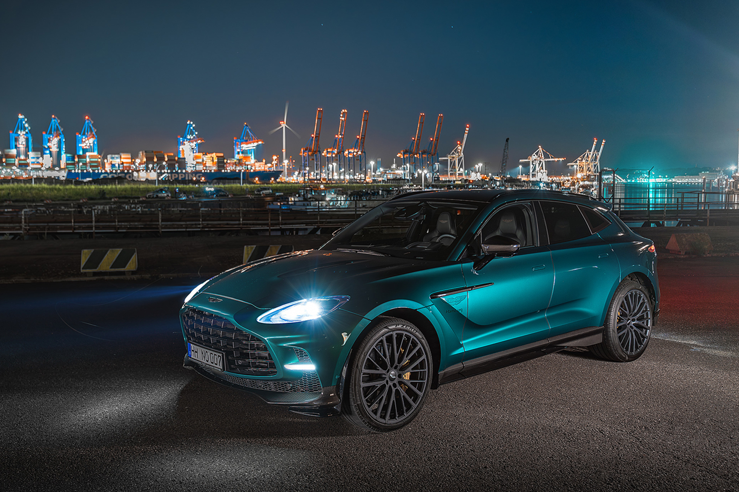 Ein Aston Martin DBX, mit dem Hamburger Hafen im Hintergrund