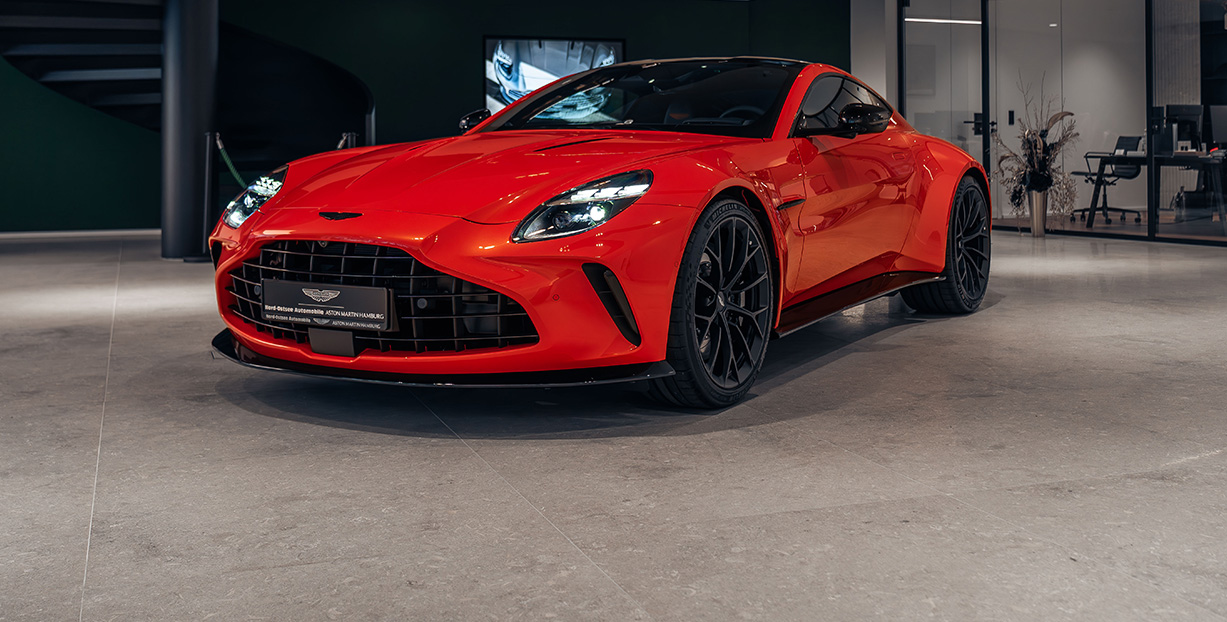 Eine Kachel: Mit einem orangenen Vanquish. Bei Mouseover sieht man ein Video mit mehreren Fahrzeugen, im Showroom.